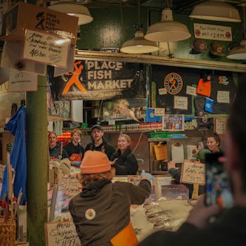 Lively atmosphere of Pike Place Fish Market with people engaged in fish tossing and sales activities.