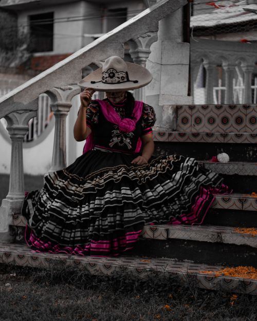 Free Woman in traditional Mexican dress sitting on stairs, wearing a sombrero. Stock Photo
