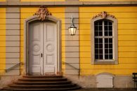 Detail of a vintage yellow building with an ornate door and lantern in Germany.