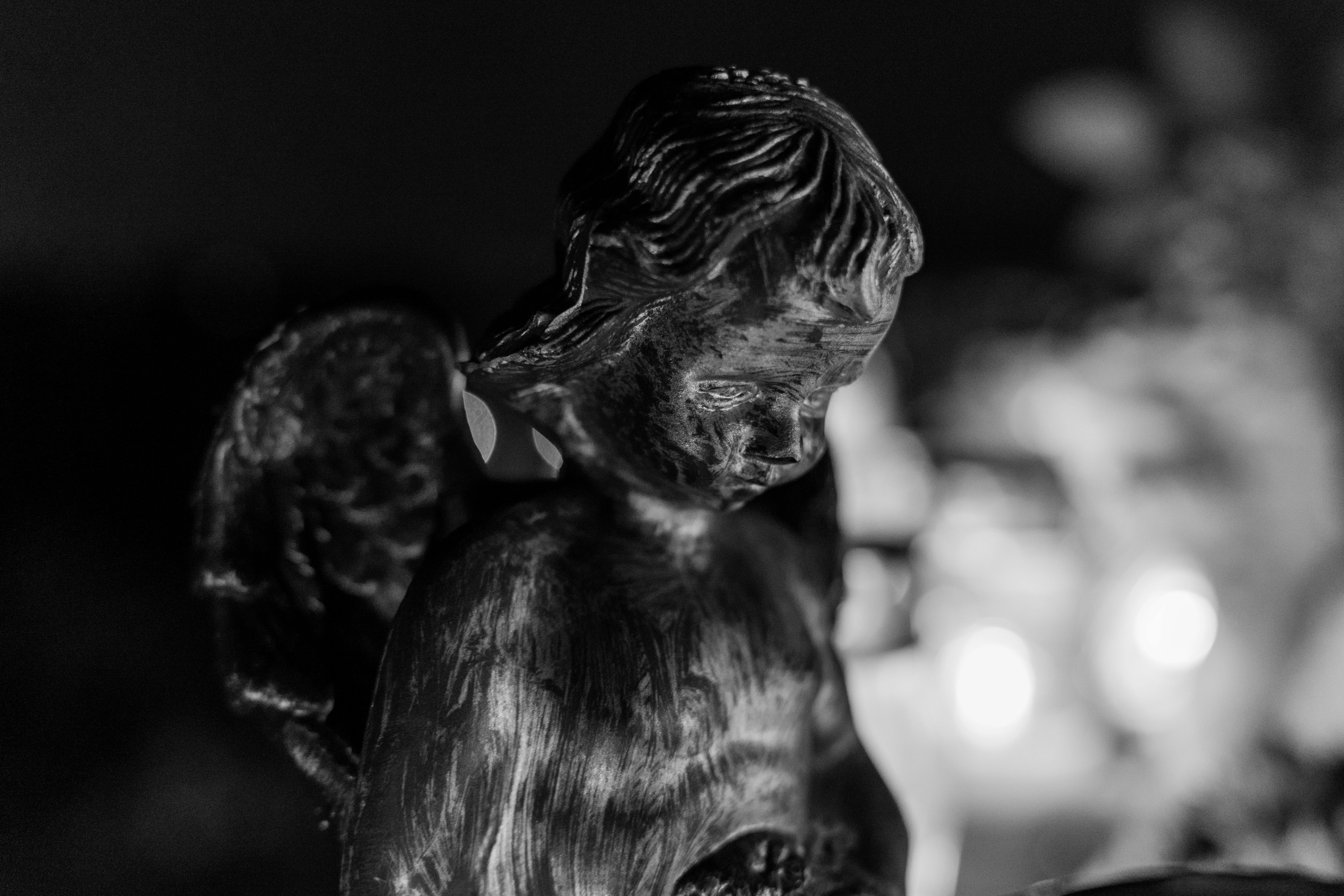 ฟรี ภาพถ่ายขาวดำของรูปปั้นเทวดาพร้อมแสงไฟอันอ่อนช้อยที่ช่วยเก็บรายละเอียดอันเงียบสงบ คลังภาพถ่าย