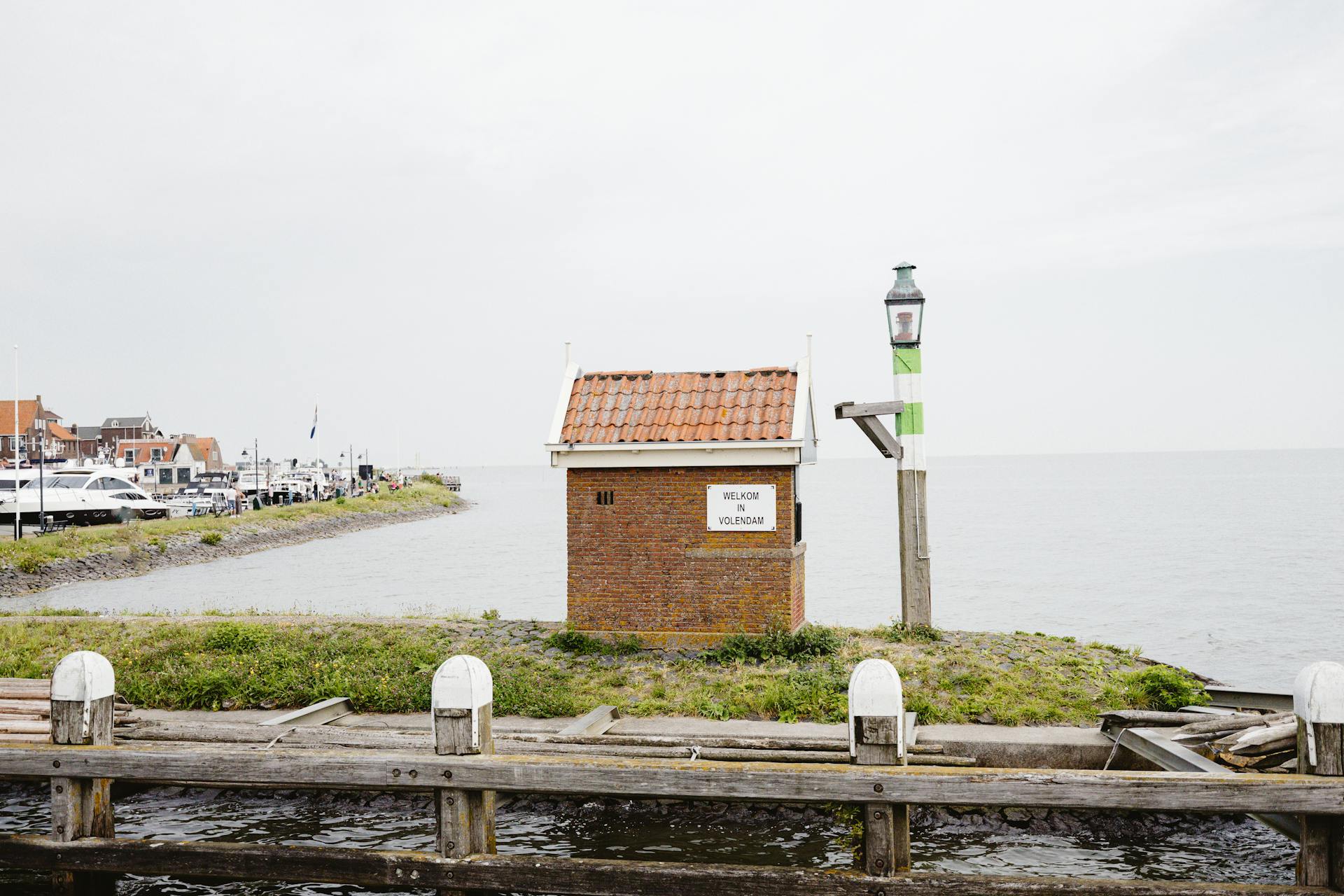Scenic view of the Volendam harbor in Netherlands showcasing water, architecture, and a welcoming sign.