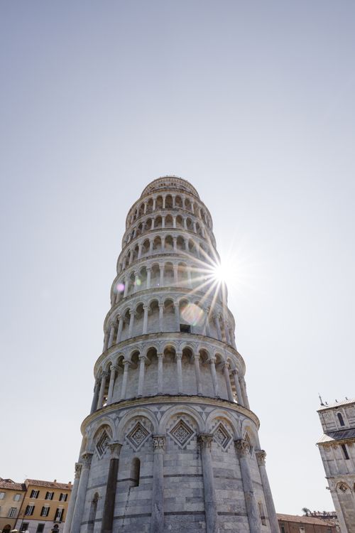 Free The Leaning Tower of Pisa with sunlight peeking through, captured from a low angle in Pisa, Italy. Stock Photo