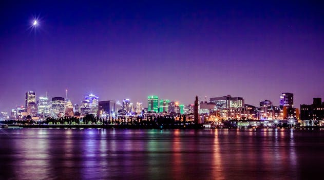 A stunning nighttime view of Montreal's skyline reflecting on the St. Lawrence River under a crescent moon.