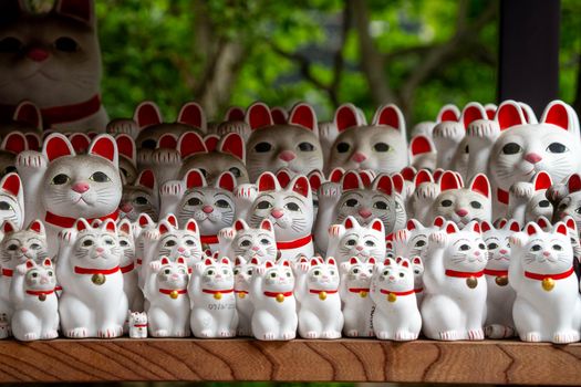 A collection of lucky cat figurines, known as Maneki-neko, displayed outdoors.