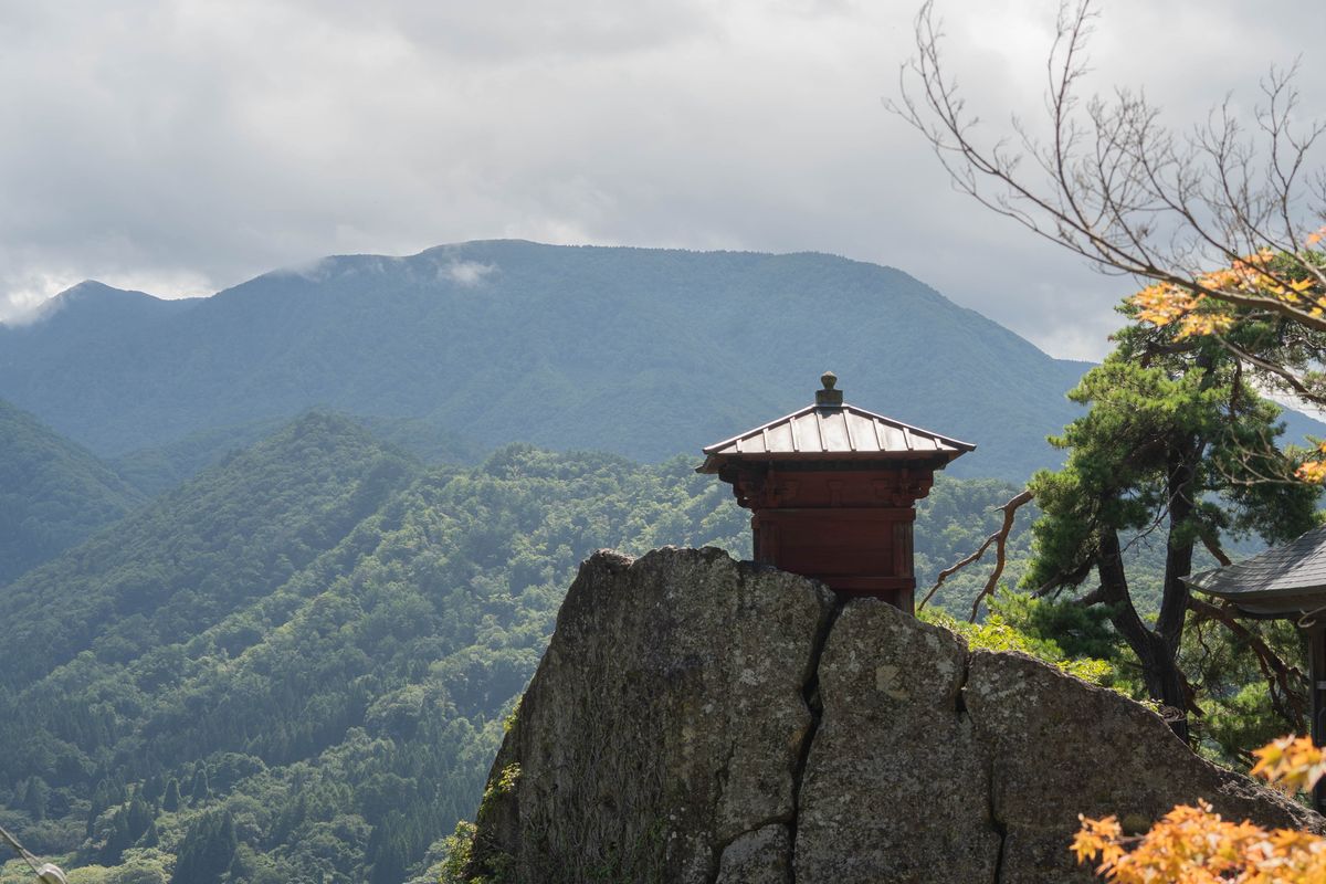 A small temple hall on a rock above a mountain forest
