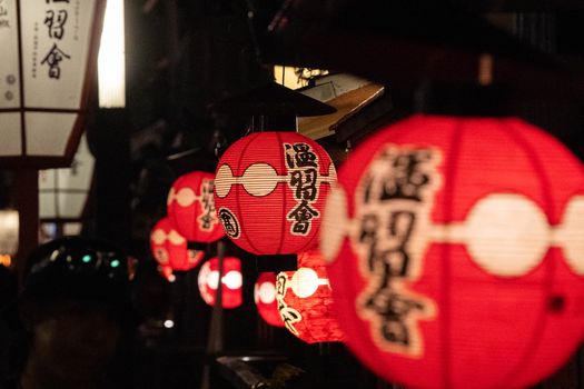 Vibrant red Japanese lanterns hanging amidst a serene night street scene, conveying cultural richness.