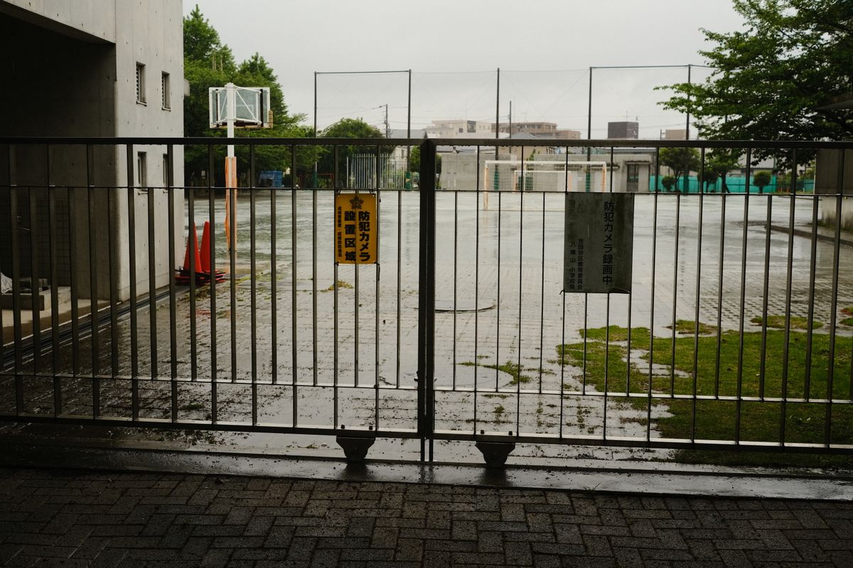 雨にぬれた小学校の校庭とフェンス