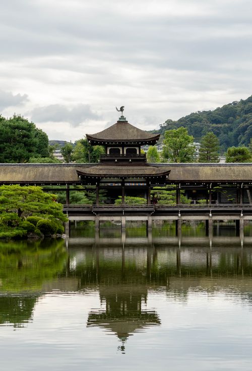 Free Traditional Japanese temple with serene water reflection and lush green surroundings. Stock Photo