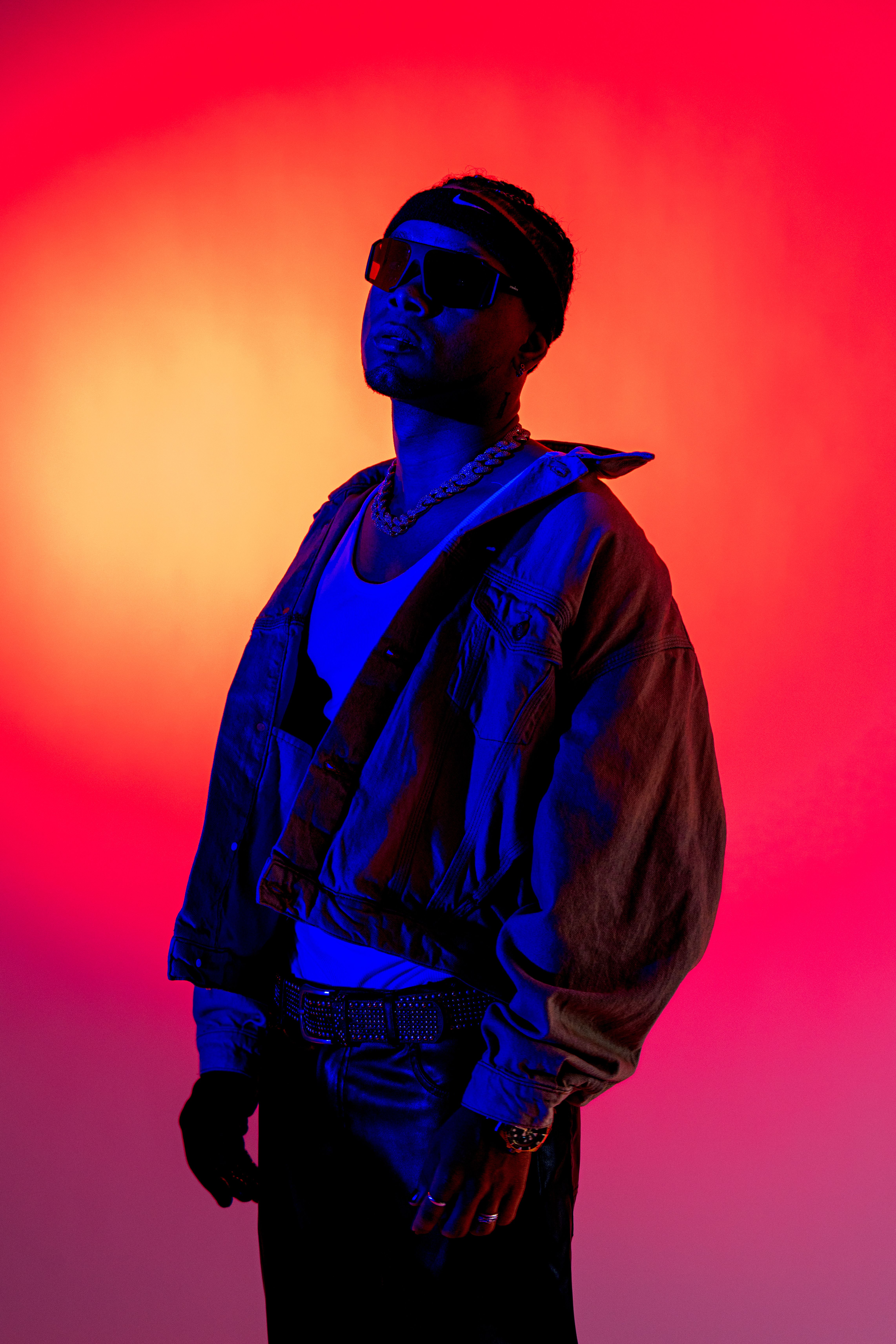 Fashionable individual in vibrant red and blue lighting, exuding confidence and style.