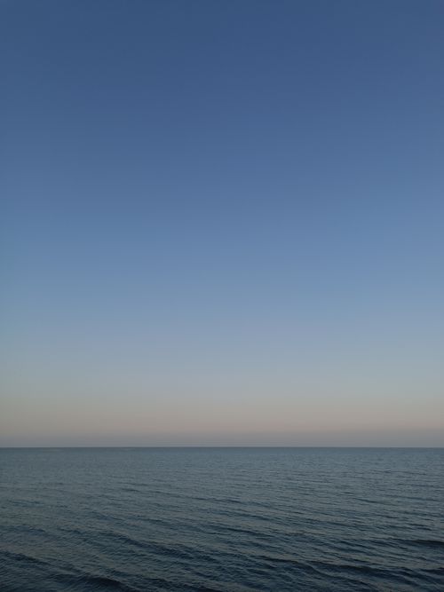 Free Serene ocean view with a clear blue sky and calm waters at dusk, ideal for peaceful backgrounds. Stock Photo
