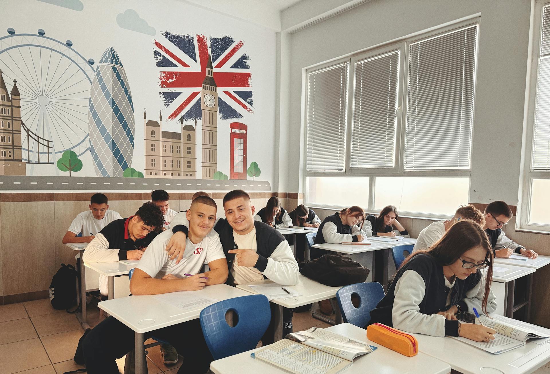 Students studying in a classroom featuring a mural of London landmarks and British flag.