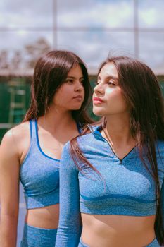 Two women in blue activewear enjoying a sunny day outdoors. Fitness lifestyle.