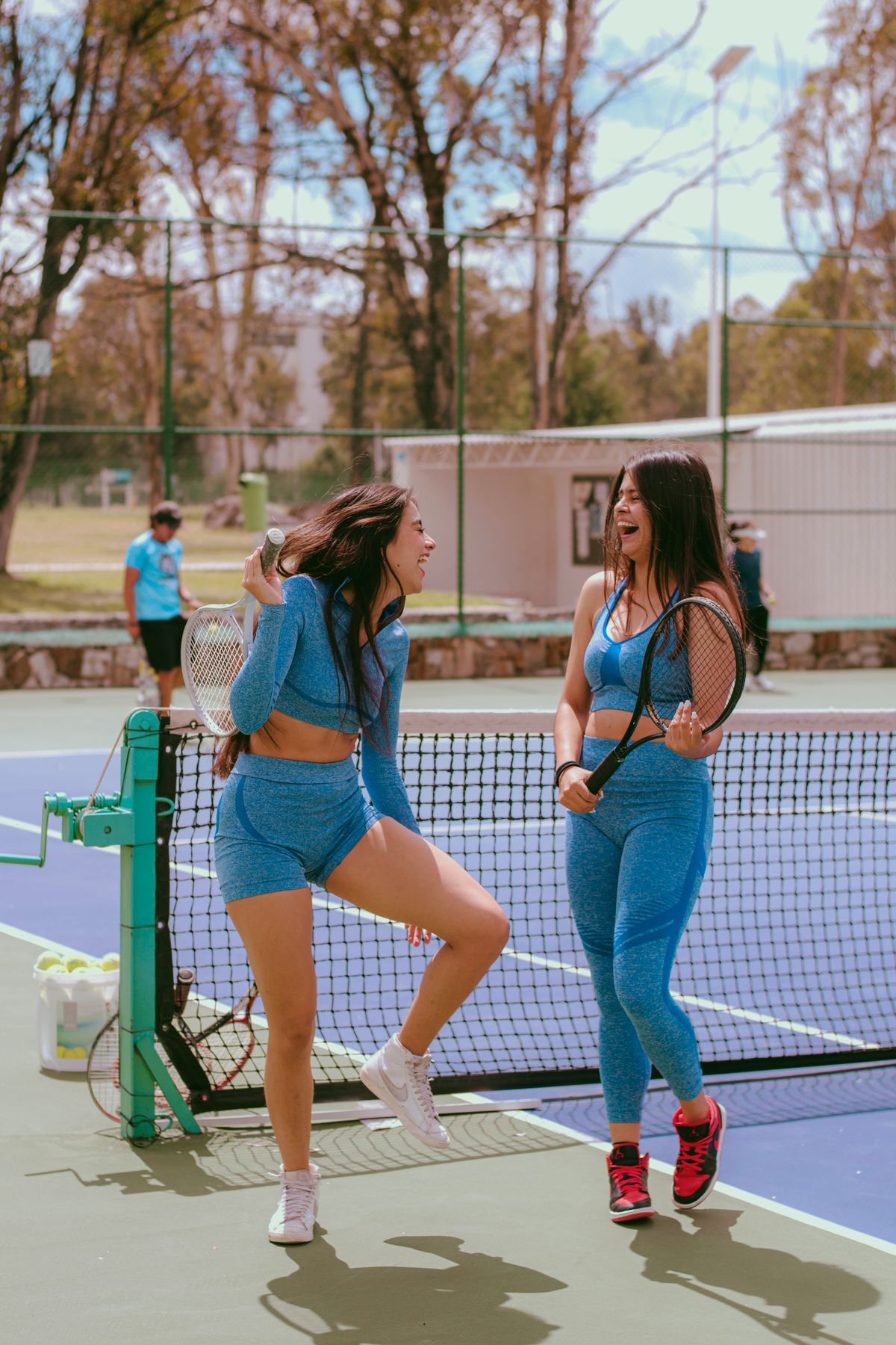 Two women laughing together at the net after a match