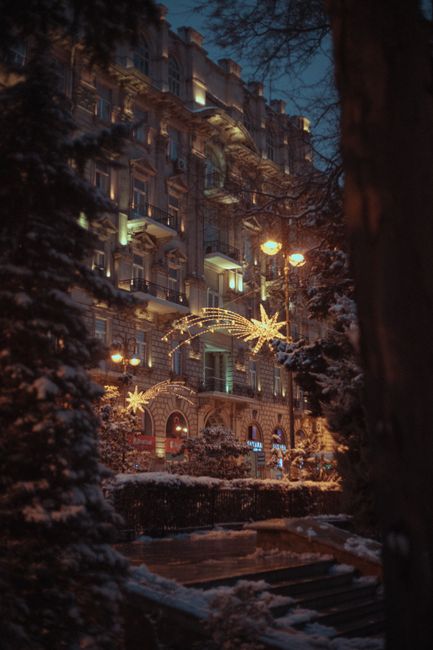 Charming winter evening street view in Baku decorated with festive lights and snow.