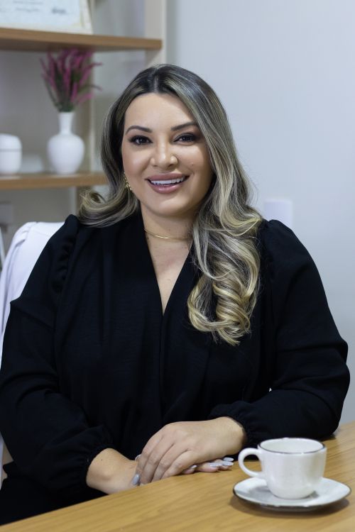 Free Confident woman in black attire smiling at desk with coffee cup, indoors. Stock Photo