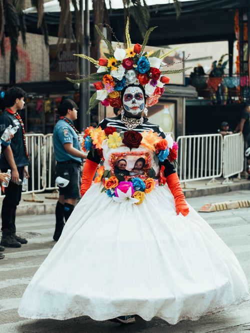 Free Colorful Day of the Dead costume featuring traditional Mexican elements, captured in a lively street parade. Stock Photo