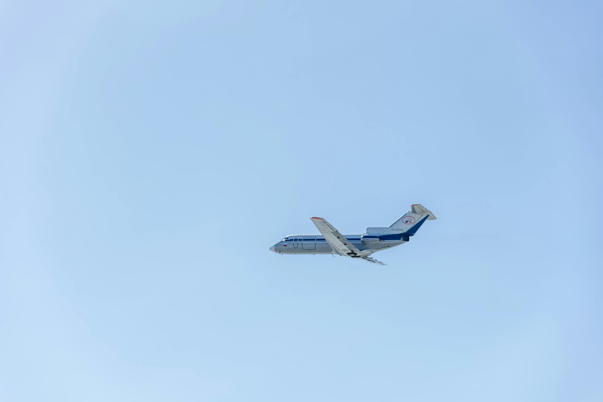 A commercial jet aircraft flies through a clear blue sky, depicting travel and aviation.