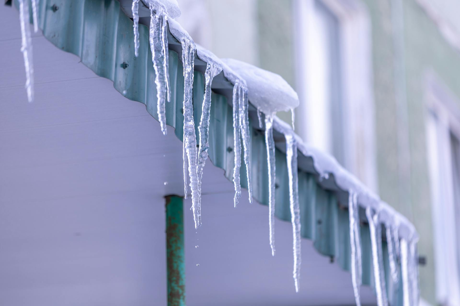 Close-up of icicles hanging from a corrugated roof during winter, capturing a frozen scene.