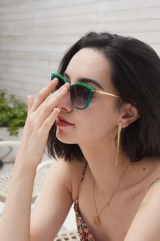 Chic woman in sunglasses poses outdoors, showcasing fashion and elegance.