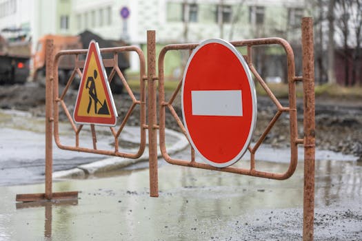Close-up of road work and no entry signs at a construction site on a rainy day.
