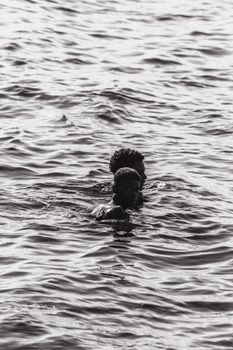 Two individuals enjoy a swim in open water, showcasing summer fun.