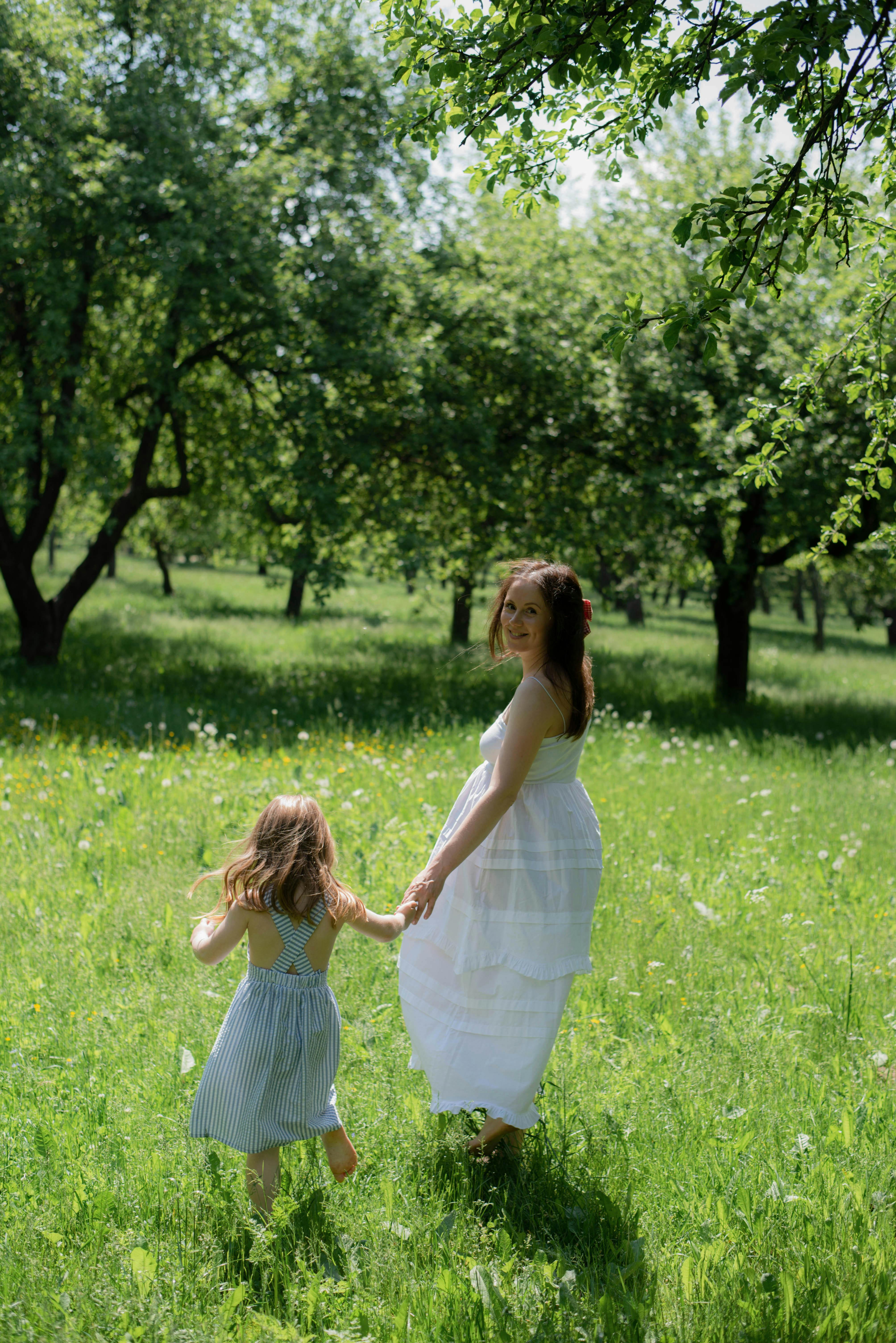 A serene walk in a sunlit orchard in Minsk, Belarus, showcasing a mother and child bond.