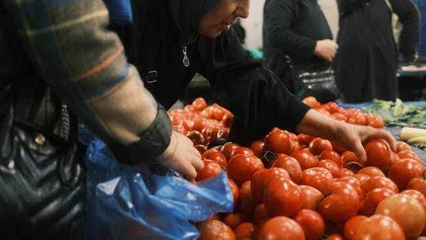People selecting fresh tomatoes at an outdoor market in Istanbul, Turkey.