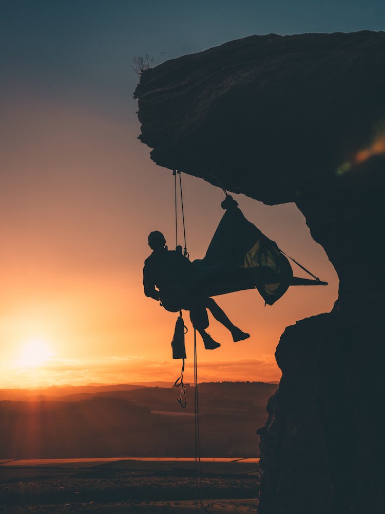 Silhouette Photo Of Person Hanging By The Cliff