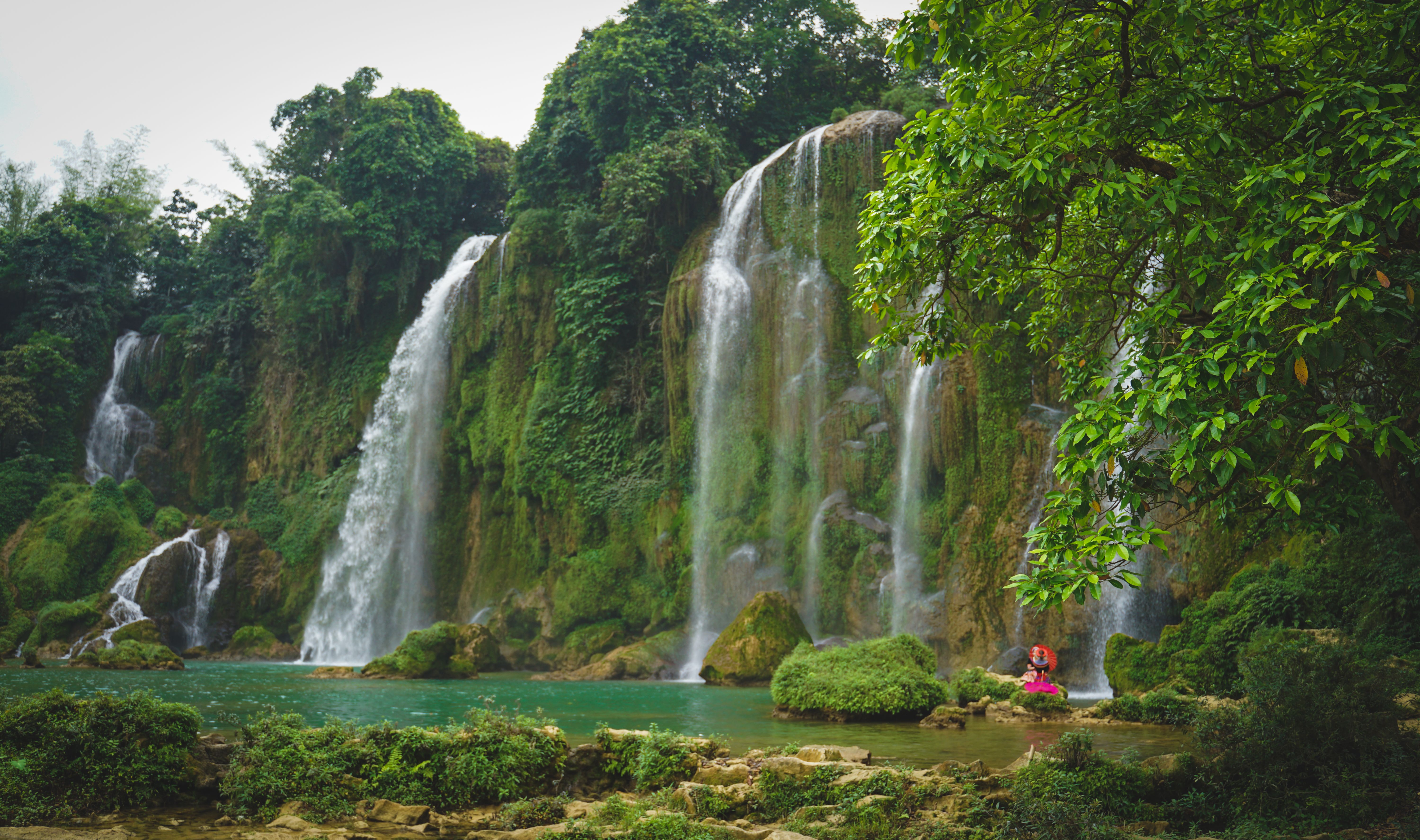 Scenic Waterfall with Lush Greenery and Traveler · Free Stock Photo
