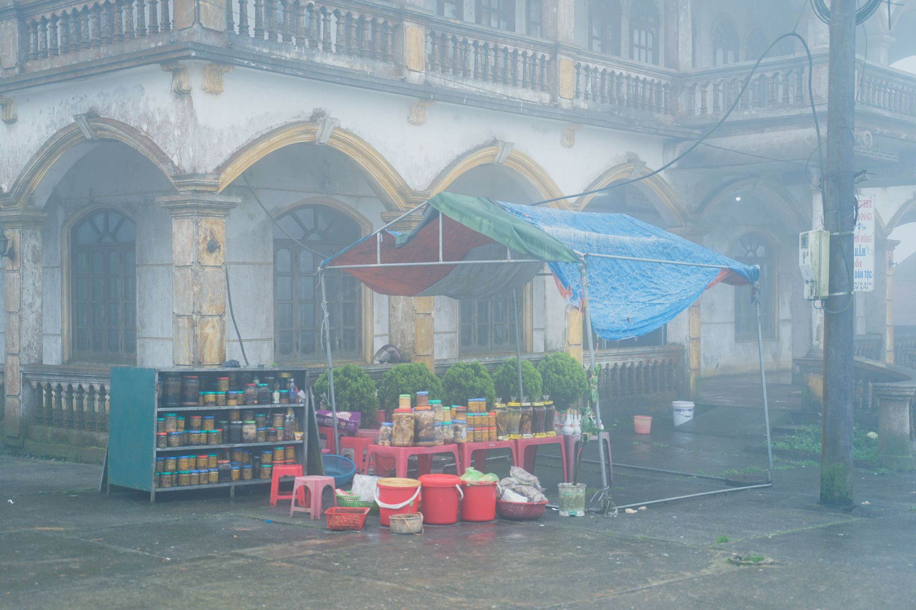 A street market stall under a misty sky with an old building background.