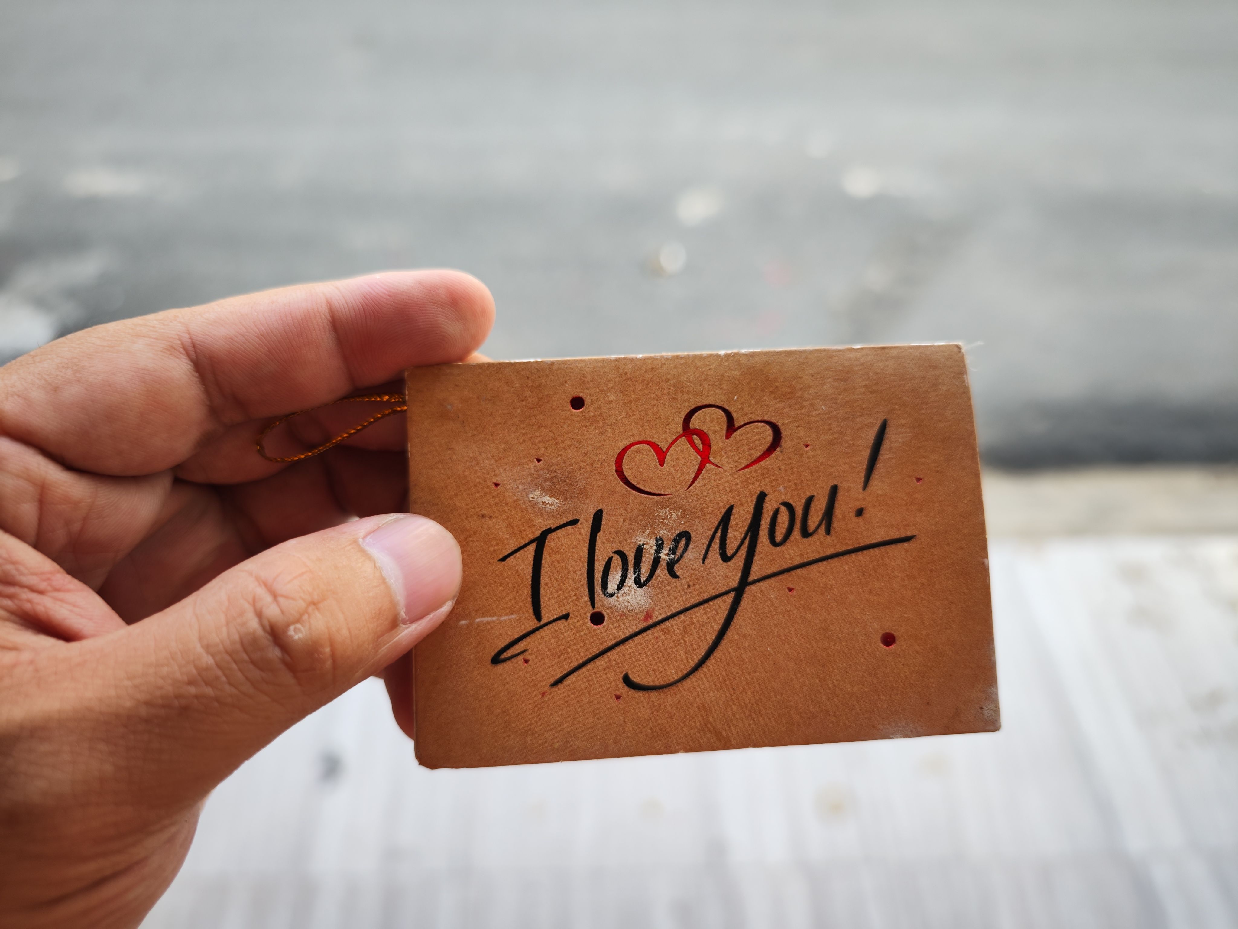 A hand holds a romantic 'I Love You' card outdoors in Ho Chi Minh City.