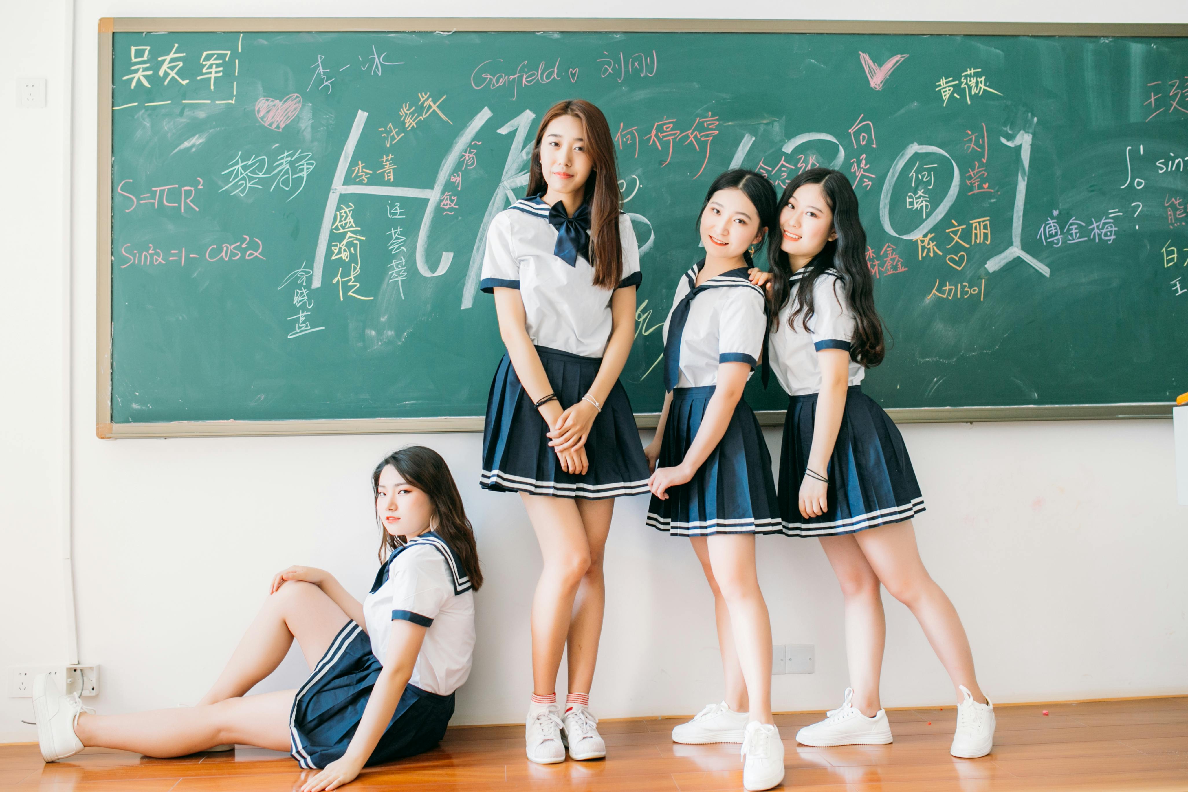 免費 四名穿著校服的青少年在寫著數學方程式的教室黑板前擺姿勢。 圖庫相片