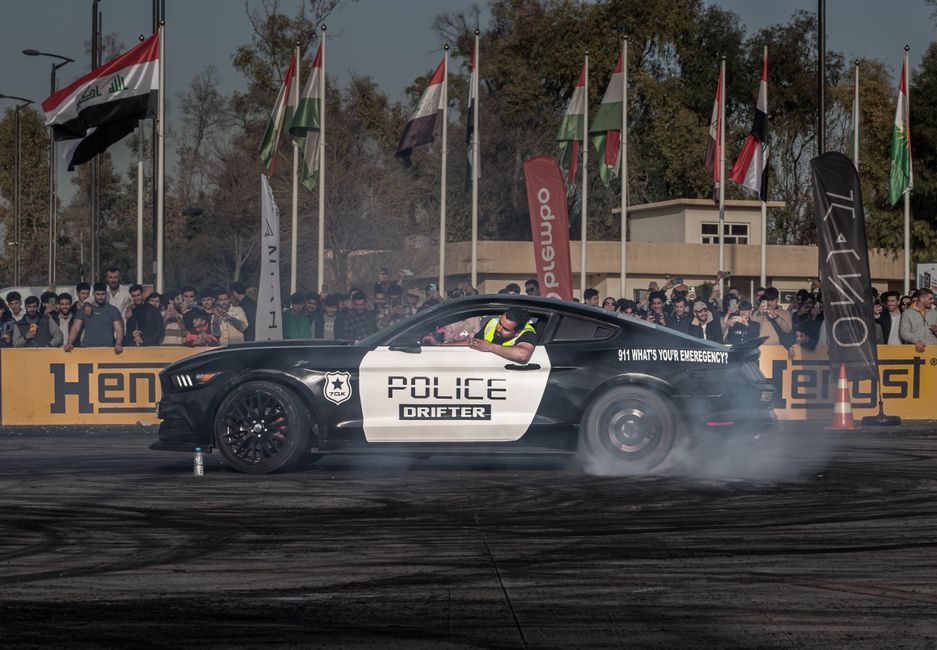 A Ford Mustang performs a drift at a vibrant car show in Erbil, Iraq.
