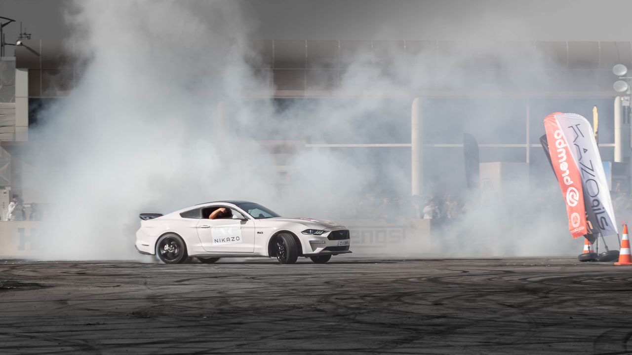 white ford mustang drifts creating smoke at an auto event in erbil ira