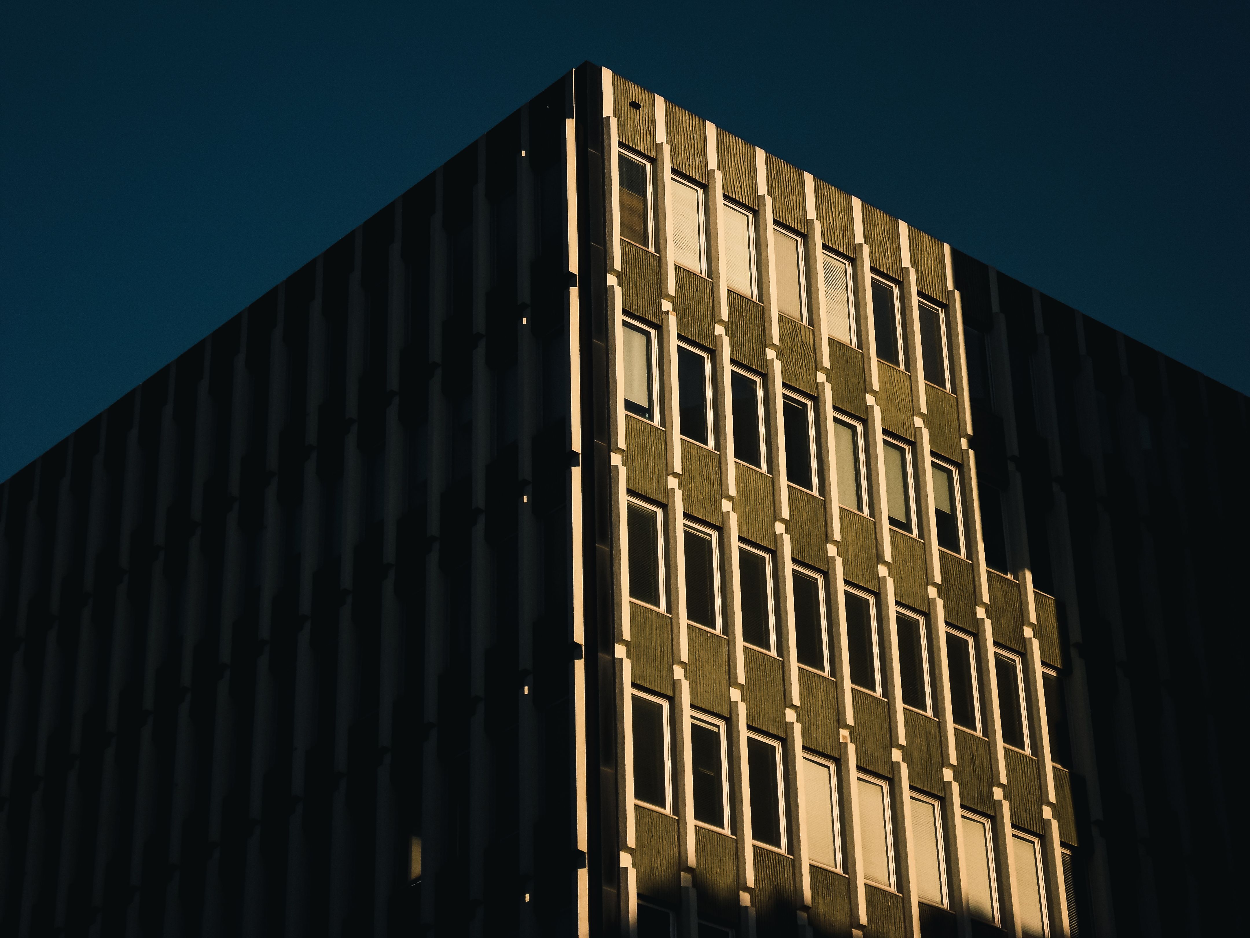 Modern building facade with geometric patterns and evening light shadows.