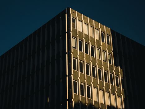 Modern building facade with geometric patterns and evening light shadows.