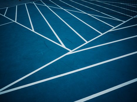 Blue tennis court with abstract white lines creating geometric patterns.