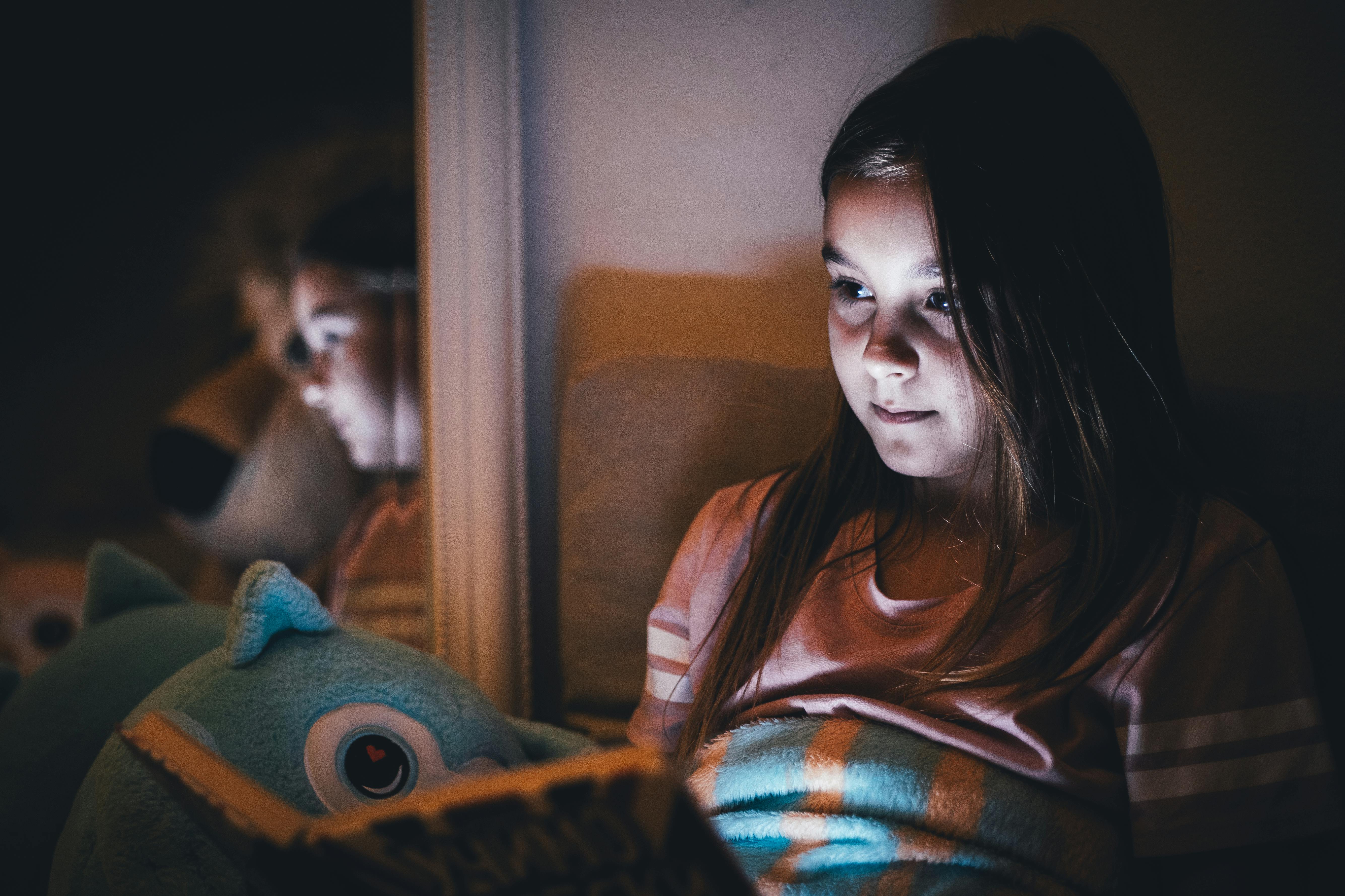 Young girl reading a book at night under soft light