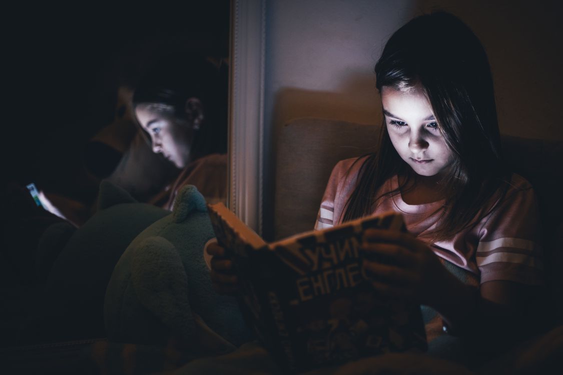 Child Reading at Night with Dim Light Reflection · Free Stock Photo