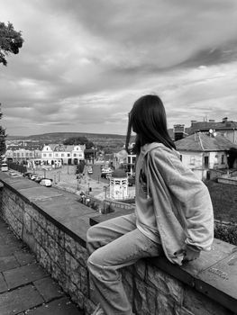 A young woman in casual attire gazes over the scenic cityscape of Chernivtsi, Ukraine.
