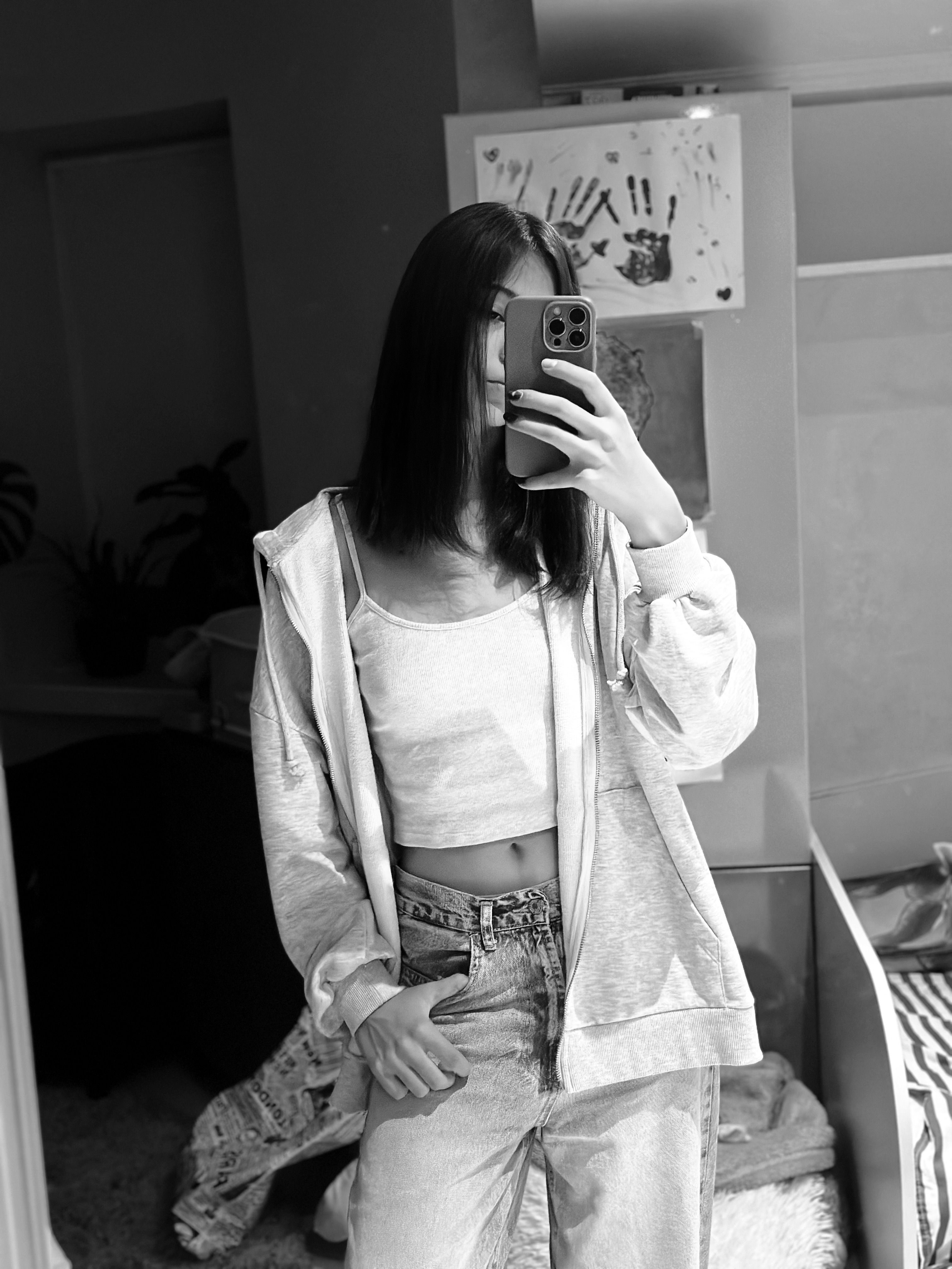 Stylish young woman takes a monochrome selfie in a mirror, showcasing casual fashion.