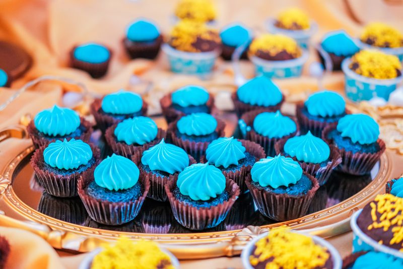 Delicious mini cupcakes with blue frosting on a decorative tray, perfect for celebrations.