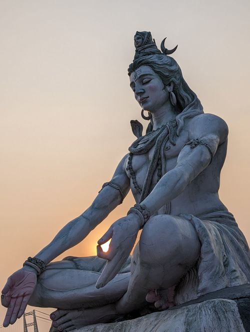 Free A majestic statue of Lord Shiva in a meditation pose during a tranquil sunset. Stock Photo