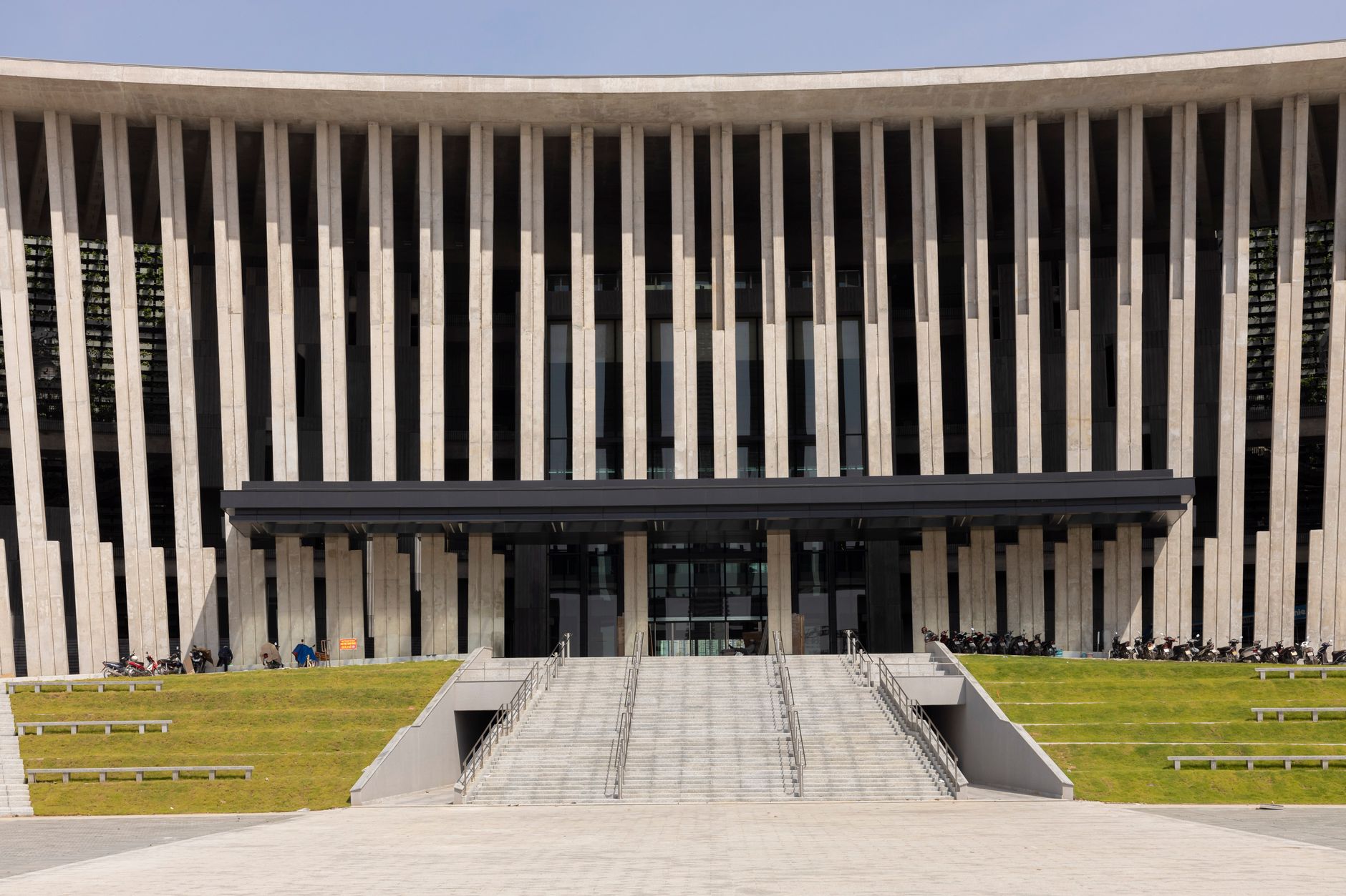 Dramatic facade of a modern architectural building with vertical columns and entrance stairs.
