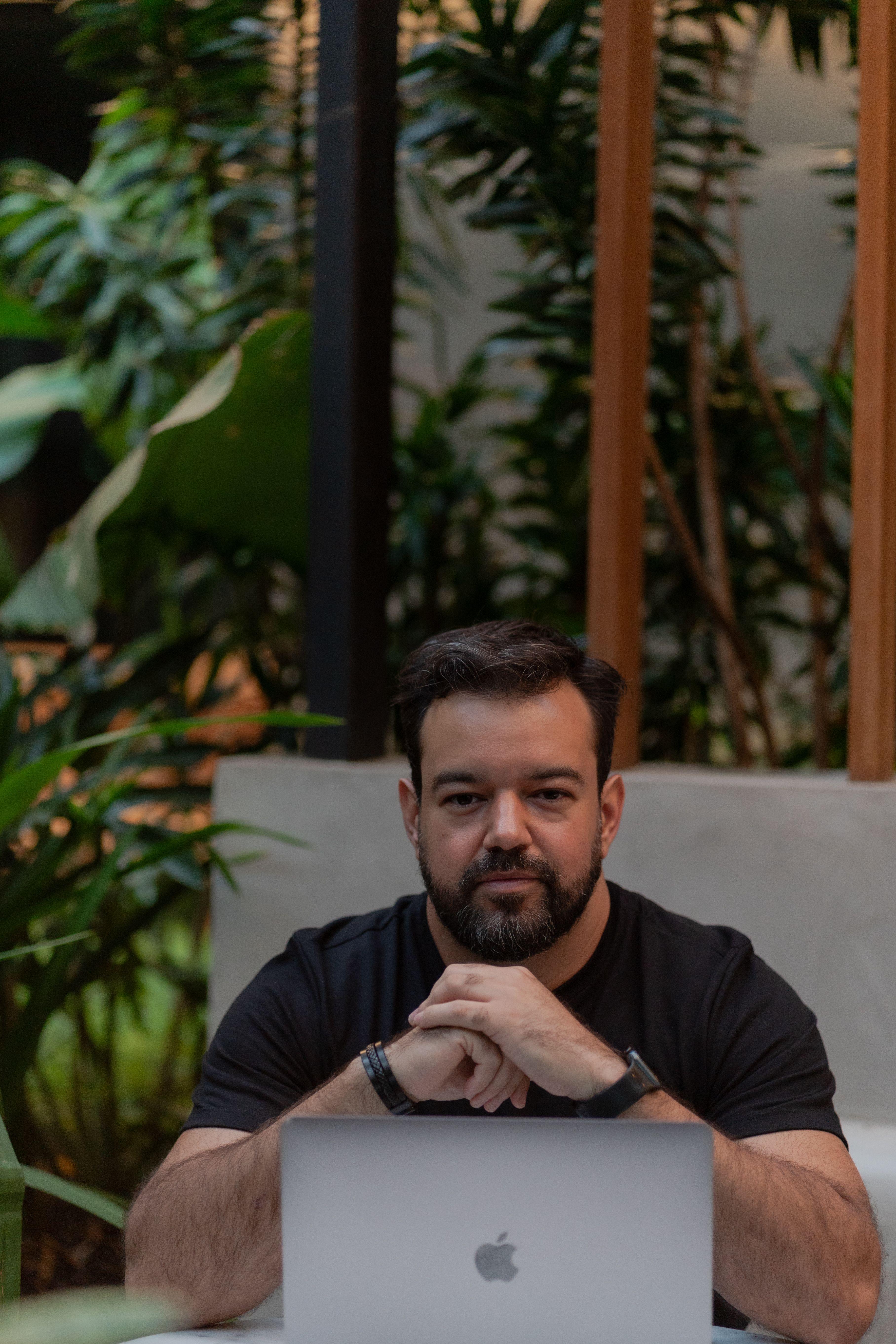 Man sitting with laptop in a serene indoor garden, focusing on work.