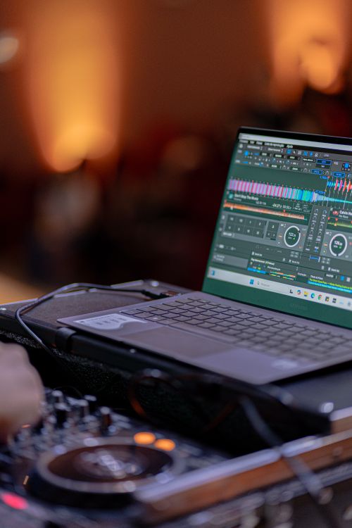 Free DJ using laptop and mixing console during a vibrant indoor event. Stock Photo