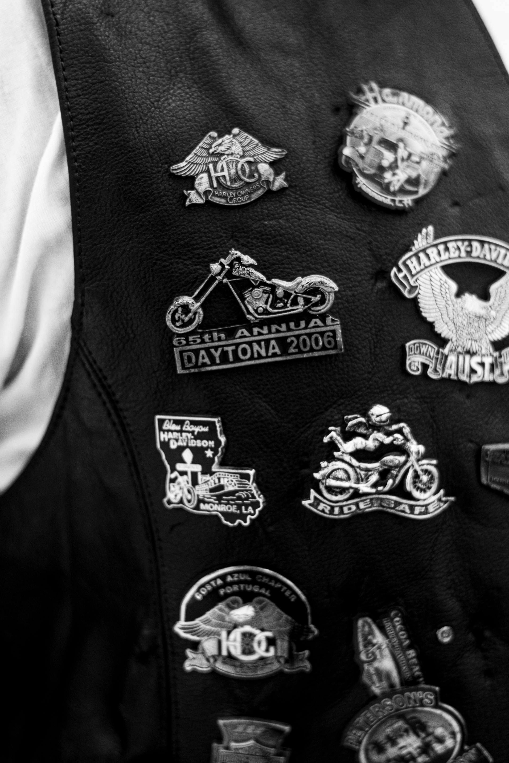 Black and white photo of motorcycle club patches on a leather vest, highlighting biker culture.