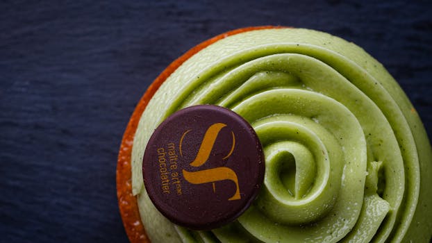 Close-up of a pistachio tart topped with chocolate on a dark slate surface.