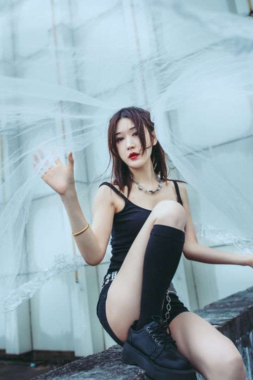 Free Stylish young woman in black dress poses gracefully in urban environment. Stock Photo