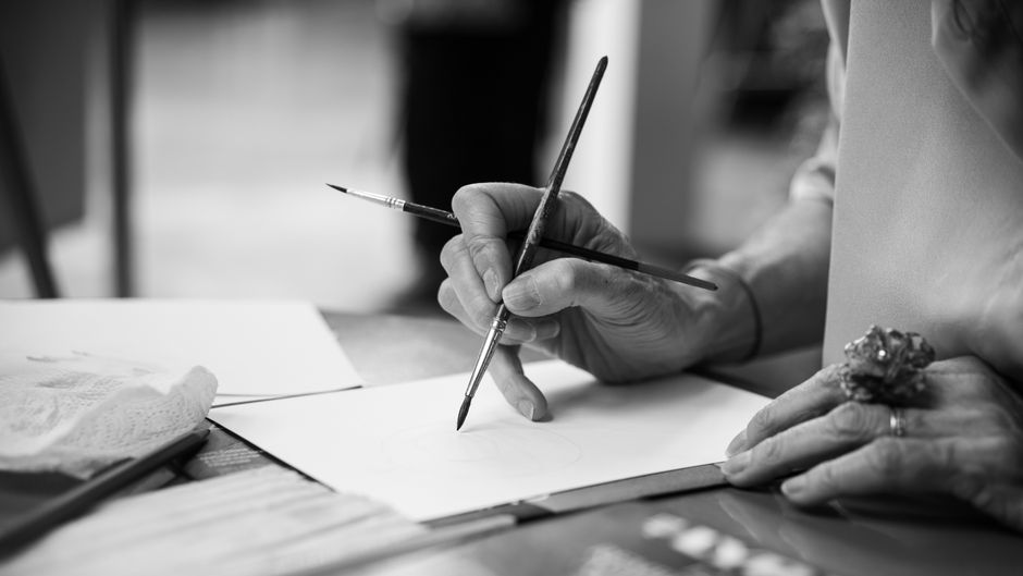 モノクロームトーンのブラシで絵を描くアーティストのクローズアップ。